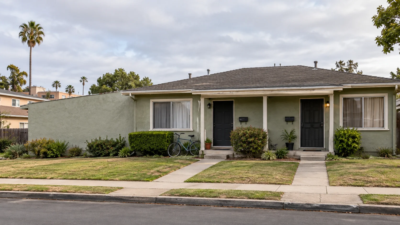 Front of a Southern California duplex with two entrances and a bicycle by the walkway